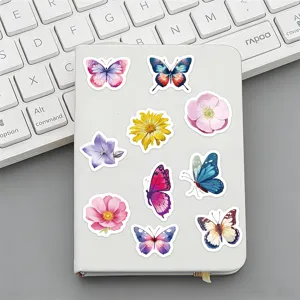 Primer plano de pegatinas decorativas de mariposas y flores en cuaderno blanco.