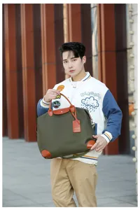 Stylish nylon travel duffel bag with leather handles, portable waterproof luggage storage bag.