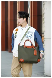Detailed outdoor view of a stylish canvas travel shoulder bag worn by a male model.