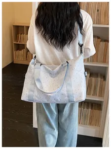 Detail shot of a light blue star print travel duffel bag, showing stylish shoulder straps.