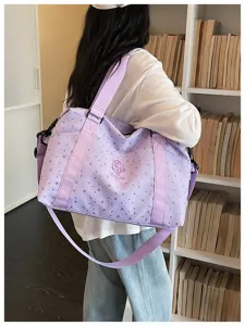 Detail shot of light purple travel duffel bag featuring star pattern and logo embroidery.