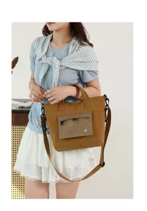Detailed view of the stylish brown canvas shoulder bag with plaid front pocket, ideal for daily commute.