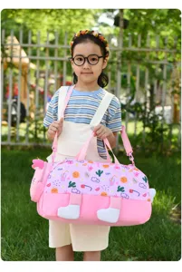 Detailed shot of a cute pink children travel duffel bag held outdoors by a child model.