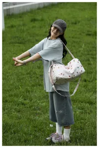 Outdoor lifestyle detail shot of a casual plaid travel duffel bag with cute star prints.