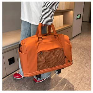 Detail shot of a large orange rolling travel duffel bag with wheels, front pocket and handle.