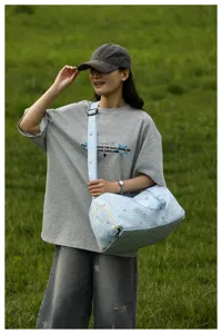 Outdoor detail shot showing the blue plaid travel duffel bag with cute heart prints being worn.