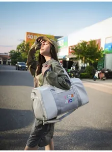 Outdoor lifestyle scene detail showing a stylish grey duffel gym bag with color text.