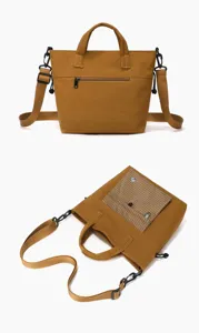 Detail view of canvas crossbody tote bag with adjustable strap, zipper pocket and plaid design.