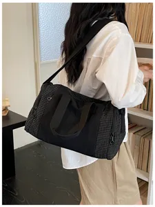 Close-up detail shot of the stylish black grid travel duffel bag worn by model indoors nicely.