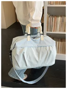 Detailed shot of large capacity travel duffel bag in light blue with grid pattern, showing handles.