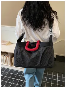 Detailed shot of the large capacity grid travel duffel bag with red handle in indoor scene.