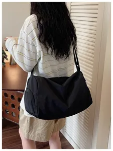 Detailed view of large capacity black travel duffel bag worn on shoulder for short trips.