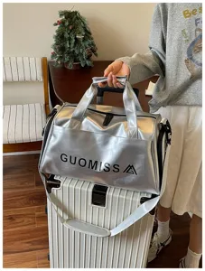 Silver metallic travel duffel bag detail shot, featuring zipper closure and sturdy handles.