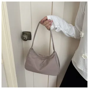 Detailed view of elegant mauve nylon hobo shoulder bag held by hand in a lifestyle setting