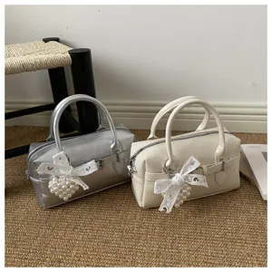 Silberne und cremefarbene Bowling-Handtaschen mit Perlenbogen auf einer Matte