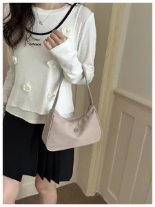 Detailed shot of a stylish light pink women's hobo shoulder bag held by a model