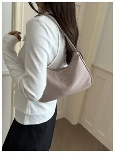 Stylish taupe nylon underarm hobo bag featuring a chic floral metal logo worn by model