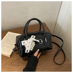 Elegante schwarze glänzende Bowlingtasche mit weißer Spitzenschleife und Perlenanhänger
