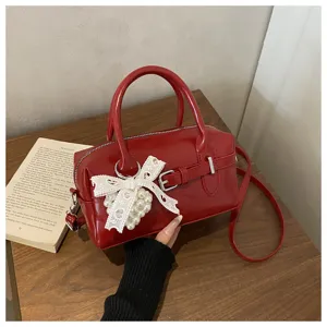 Detailansicht einer roten Bowling-Handtasche mit weißer Spitzenschleife und Perle