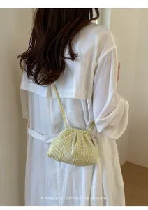 Detailed back view of a yellow gingham checkered pleated cloud bag on a white dress