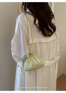 Detailed back view of model carrying a yellow striped mini crossbody bag in retro style