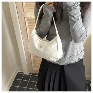 Detail showing the elegant white nylon armpit shoulder bag with its metallic logo badge