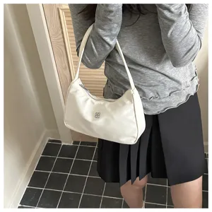 Detail view of a stylish white nylon underarm bag featuring a silver four-leaf clover logo