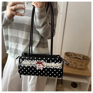 Detailed view of stylish black polka dot shoulder bag featuring white lace trim and red bow