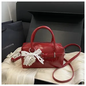 Detailansicht einer roten Bowlingtasche mit Spitzenschleife und Perlenherz-Anhänger.