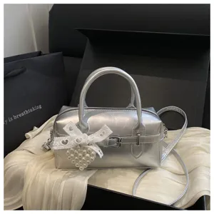 Detailansicht der silbernen Bowling-Handtasche mit Spitzenschleife und Perlenherz-Anhänger