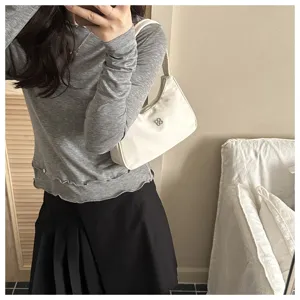 Elegant minimalist white underarm shoulder bag styled with grey top and black skirt.
