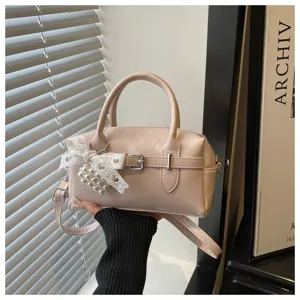 Nahaufnahme einer rosa Handtasche mit Spitzenschleife und Perlenanhänger