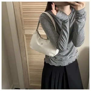 Elegant white minimalist underarm shoulder bag shown on a female model in a lifestyle setting