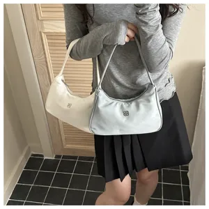 Two minimalist underarm bags in white and light blue held by a stylish model