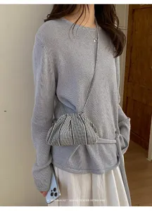 Close-up of a striped plaid small crossbody bag worn by a model in a retro style
