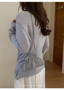 Detailed view of striped checkered crossbody bag styled with a lavender knit sweater.