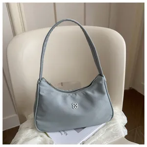 Elegant light blue nylon hobo shoulder bag with a silver clover logo shown in a lifestyle setting