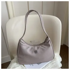 Detailed view of a mauve nylon hobo shoulder bag featuring a silver clover metal logo