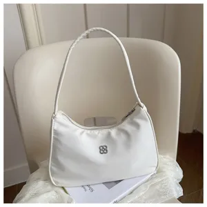 Detailed view of elegant white nylon underarm bag with silver floral clover logo