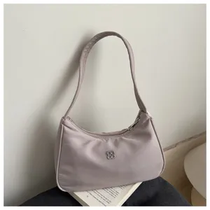 Minimalist dusty rose nylon underarm bag with decorative silver clover logo detail