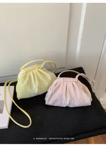 Detail view of pink and yellow gingham pleated handbags on a black textured surface