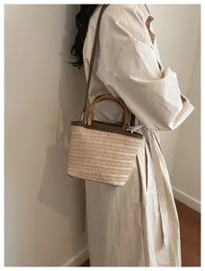 Detailansicht einer Stroh-Eimertasche mit natürlichem Bambusgriff an einem Model