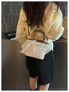 Detail einer lässigen gewebten Beuteltasche mit Bambusgriff und Spitzenschleife am Modell
