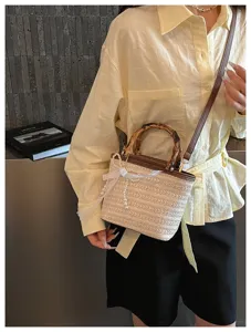 Modische geflochtene Beuteltasche mit Bambusgriff und Perlen-Schleife am Modell.