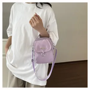 Dettaglio di una piccola borsa a tracolla in nylon viola indossata da modella