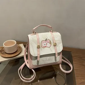 Dettaglio di un grazioso mini zaino rosa con motivo marmoreo e toppa a forma di mela