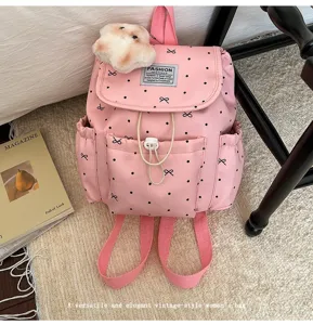 Detailed shot of pink polka dot drawstring backpack with charming black bow patterns