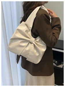 Vue de côté d'un grand sac cabas à nœud crème porté avec un blazer marron