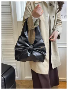 Vue détaillée d'un sac fourre-tout noir avec un grand nœud porté par un mannequin