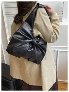 Grand sac fourre-tout noir en forme de nœud porté par un mannequin en trench-coat